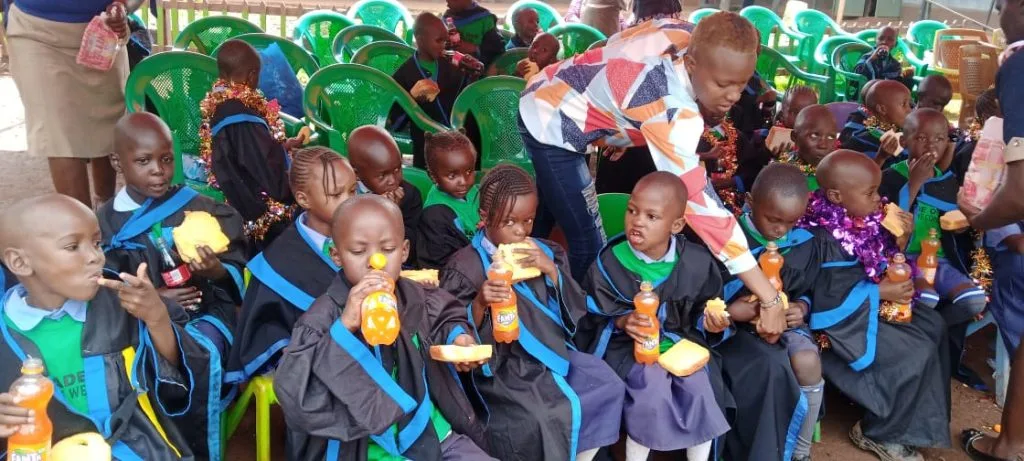 Children celebrating graduation in school uniforms and colourful headwear