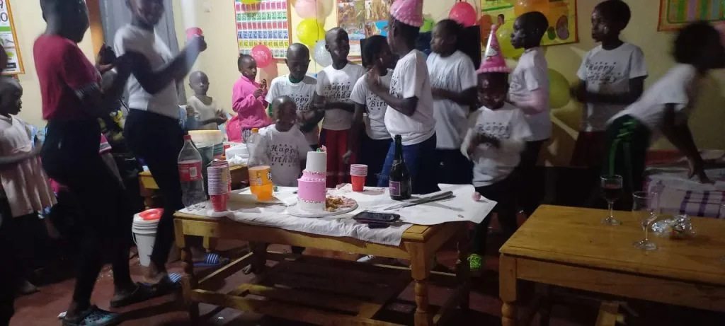 Children and adults gathered around a celebration table at Restoration