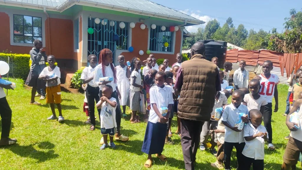 Children gathered for an outdoor community activity near classrooms