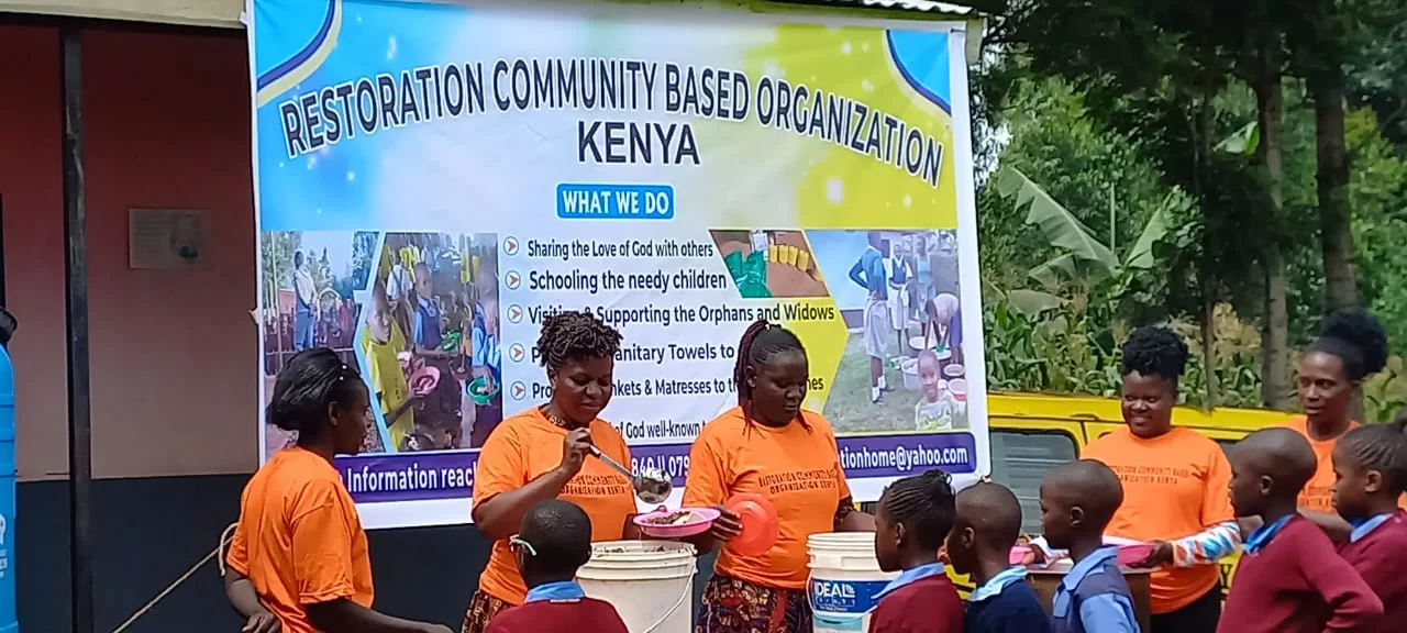 Children gathered beside the Restoration Community Based Organization banner in Kisii